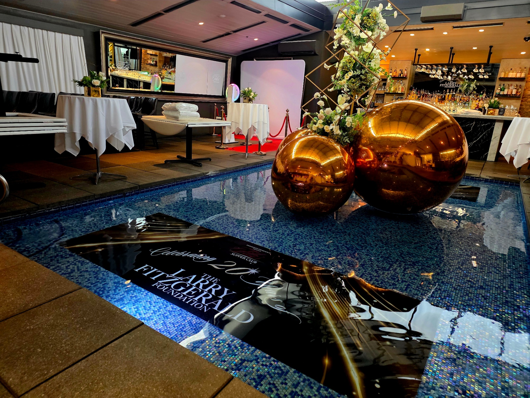 Luxury Larry Fitzgerald Foundation event installation with gold spheres and floral arrangement over reflective pool
